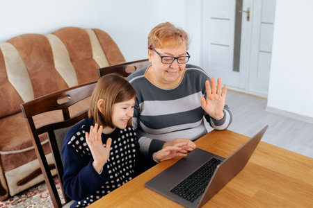 Grandmother and granddaughter enjoying video call at home togetherの写真素材