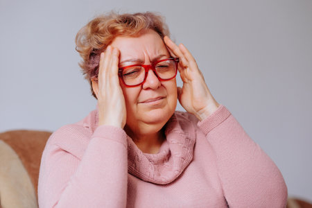 Woman experiencing headache at home during daylight hoursの写真素材