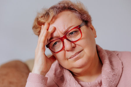 Woman with glasses showing signs of distress during thoughtful reflectionの写真素材