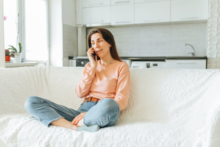 Woman engaging in a phone conversation while relaxing at home in the morningの写真素材