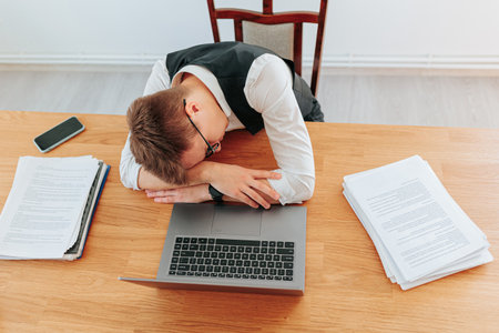 Worker feeling exhausted during late-night project at deskの写真素材