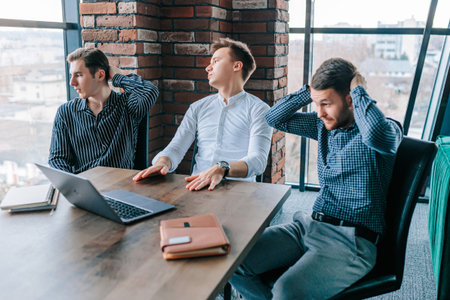 Group of men feeling upset at office meeting after experiencing business failure and crisis impacting job performance and moraleの写真素材