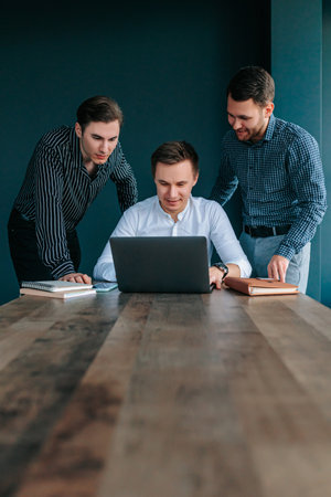 Group of young professionals discussing strategy around desk in modern office settingの写真素材