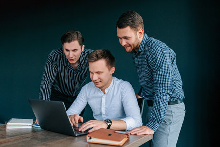 Three young professionals collaborate in a modern office, sharing ideas and strategies for their latest projectの写真素材