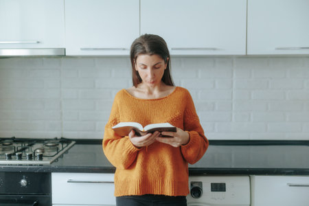 Daily self-care A young woman enjoys a reflective moment with a bookの写真素材