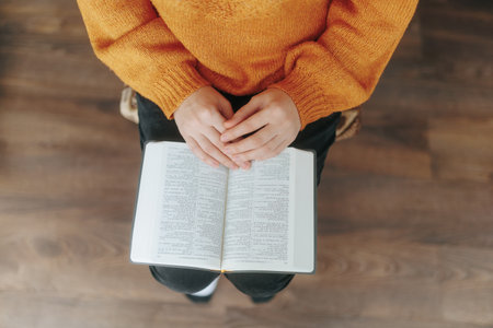Person is sitting on a chair with a book in their lapの写真素材