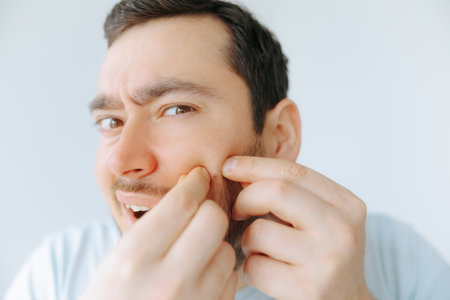 Man performs grooming routine while examining his facial hair at homeの写真素材