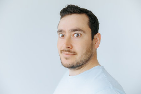 Man with a surprised expression posing against a plain backgroundの写真素材