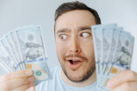 Excitement over cash: man holds money with joy and surprise