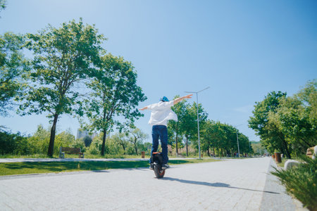 Joyful Man Balancing on a Monowheel in a Lush Urban Parkの写真素材