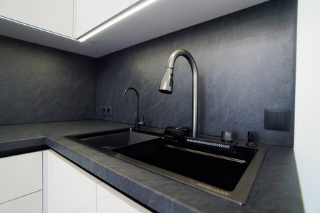 Modern black kitchen sink area with sleek design and elegant faucet featuresの写真素材