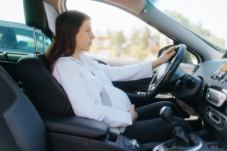 Young pregnant woman driving a car on a sunny dayの写真素材