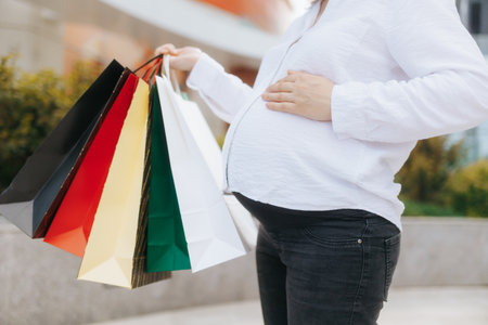 Young pregnant woman enjoying shopping day with colorful bagsの写真素材