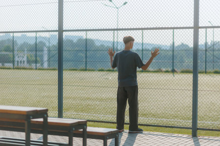 Teen Standing Alone by the Empty Sports Field, Deep in Thoughtの写真素材