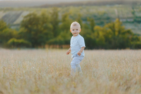 Little boy walks through tall grass, focused on his tiny stepsの写真素材