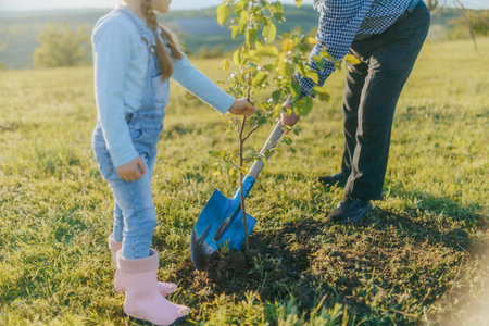 Grandpa and Granddaughter Planting a Tree in the Springtime