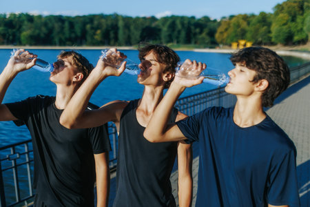 Teenagers Drinking Water Together Outdoors After Sunset Exercise