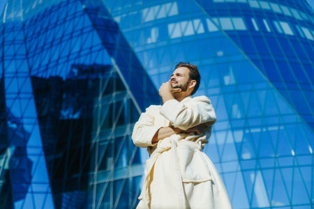 Playful businessman in bathrobe standing proud near modern corporate tower
