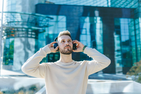 Handsome Bearded Man Listening to Music with Headphones in Modern City