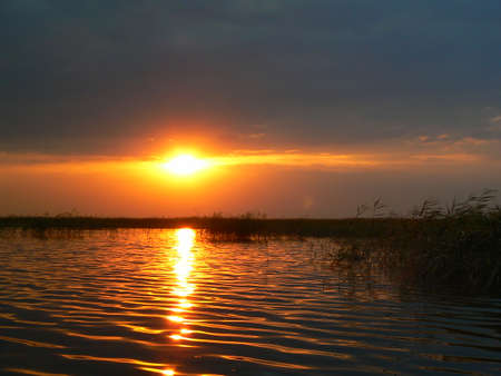Autumn sunset over the lake, the sun sets over the horizon. At the beginning of Autumn, the sunset is crimson.の写真素材