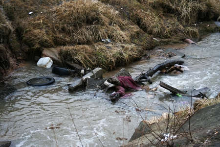 Garbage in the river after the snow melts. Environmental pollutionの写真素材