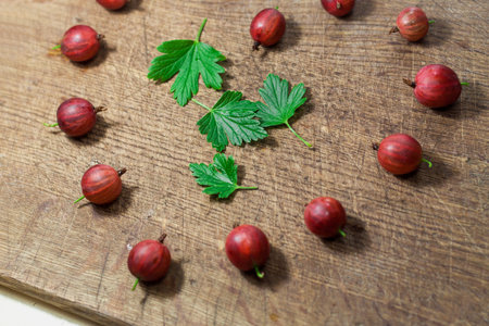 Red gooseberries on a wooden background in the shape of a heart. Close up gooseberries. Side viewの写真素材