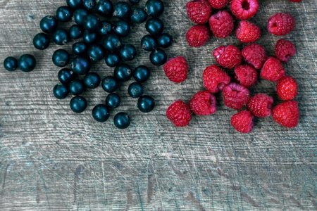 Mixed berries background with ripe delicious raspberries and black currants in fifty fifty...
