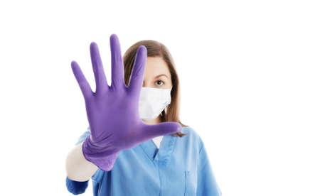 Young doctor wears gloves and medical mask  gesturing with hand no and stop spreading viruses. Prevention concept of infections and pandemic virus. Portrait isolated on white background.の写真素材