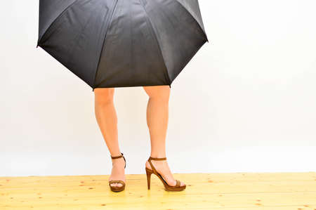 woman s legs on high heels  under black umbrella on white backgroundの写真素材