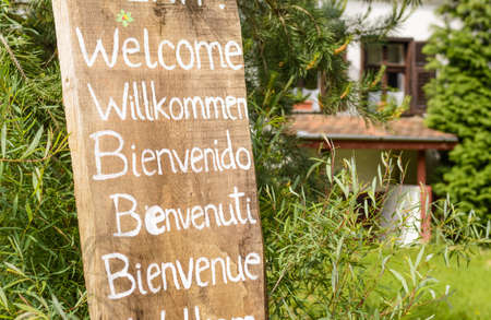 welcoming sign written with white paint on an old piece of wood in different languagesの写真素材