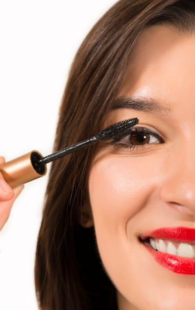 Close up portrait of beautiful young woman applying mascara