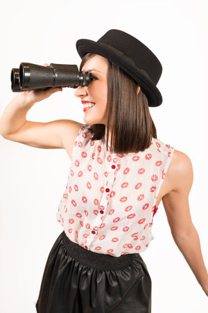 Young woman looking through a binocular, studio shot on white background. Looking for summer...