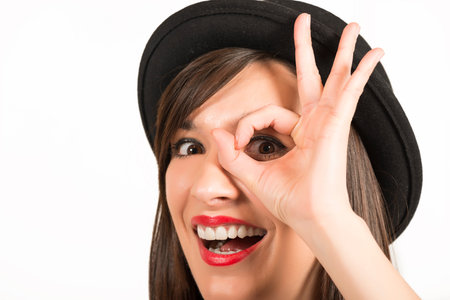 Portrait of a happy expressive beautiful girl with black hat sanding a kiss to you, studio shot on...