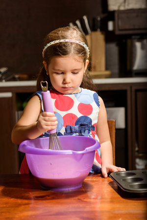 Little Girl Baking Cookies. Beautiful daughter helping her mother to prepare muffinsの写真素材
