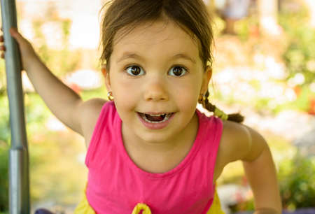 Outdoor portrait of expressive beautiful little girl smiling looking at the cameraの写真素材