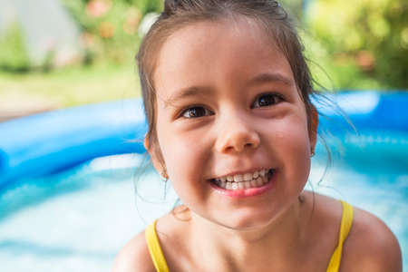 Adorable little girl playing at a outdoor swimming pool in a sunny summer dayの写真素材