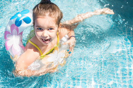 Adorable little girl playing at a outdoor swimming pool in a sunny summer dayの写真素材
