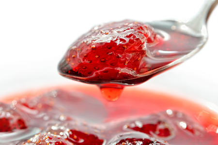 Strawberry jam is stirred with a spoon on a white background. Fruit dessert close up. Confectionery.の写真素材