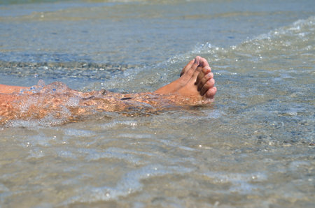 Feet in the water while relaxing on the beach. Vacation at seaの写真素材