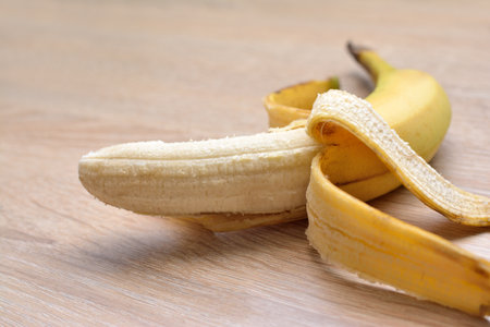 Partially peeled banana on a wooden table, close-upの写真素材