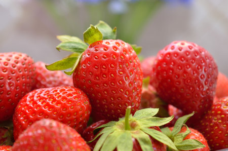 Fresh red strawberries with green leaves and blurred floral backgroundの写真素材