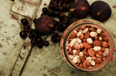 Jar of seeds with figs and grapes in the background.の写真素材