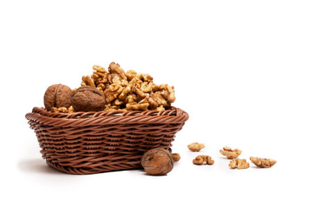 Basket of walnuts, with some on the table, isoalted on white.の写真素材