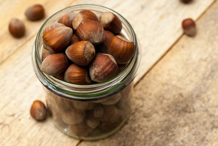 Transparent jar full of hazelnuts, home decore, on wooden table.