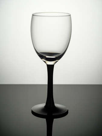 An empty shot glass with a black leg stands on a gray tableの写真素材