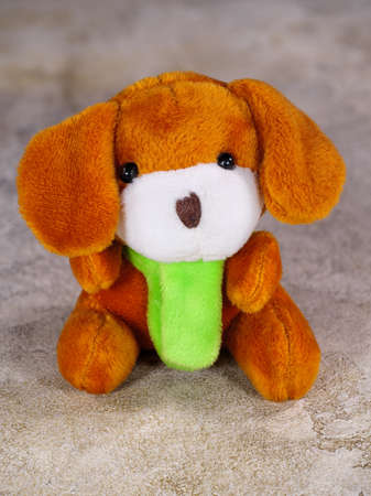 Cute brown plush puppy toy sitting on gray boardの写真素材
