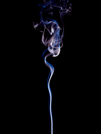 A thin stream of blue and white smoke rises gently upwards against the black backgroundの写真素材