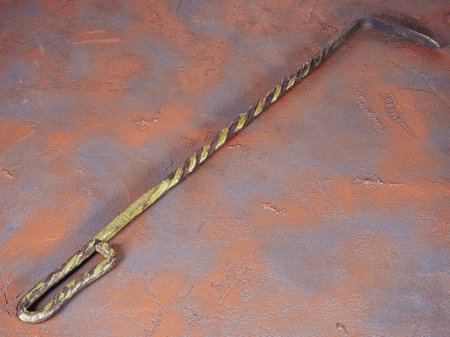 Metal poker for coals as fireplace accessories on a grunge rusty backgroundの写真素材