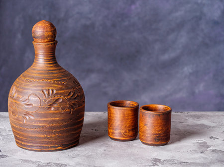 Clay pitcher and two ceramic shot glasses on a grunge style backgroundの写真素材