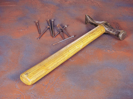 An old hammer with a wooden handle and a bunch of rusty nails on a grunge style backgroundの写真素材